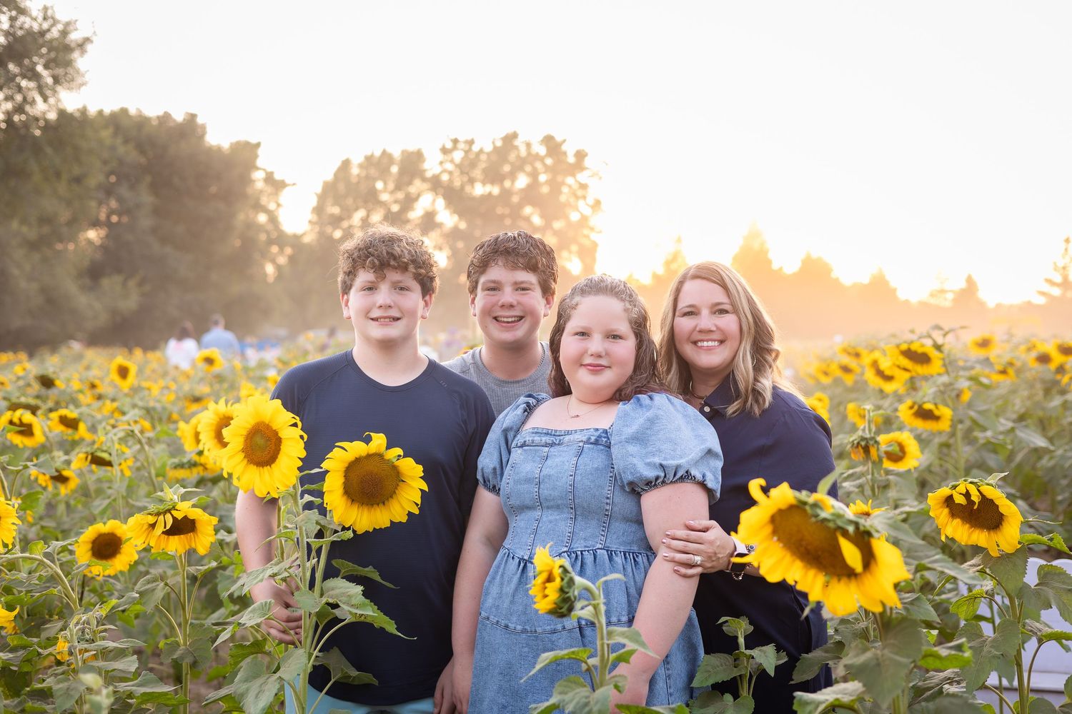 Sunset photoshoot in a field of blooming sunflowers with golden light.