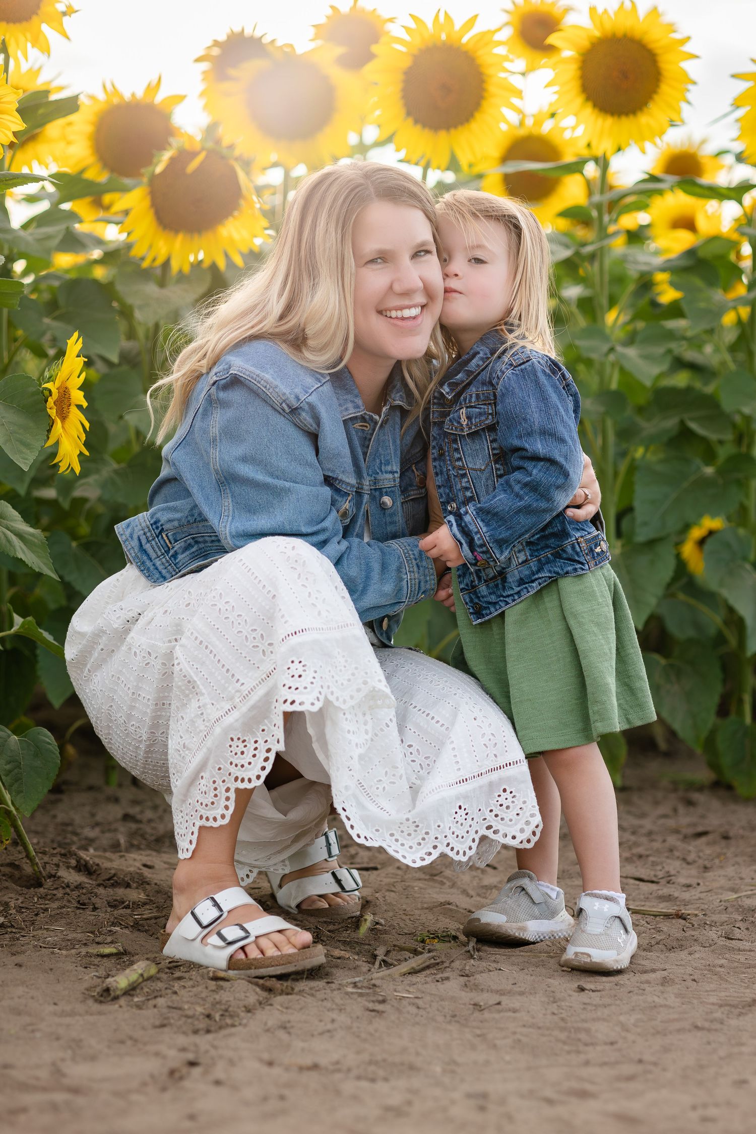 White lace dress and denim jacket details against sunflower field background.