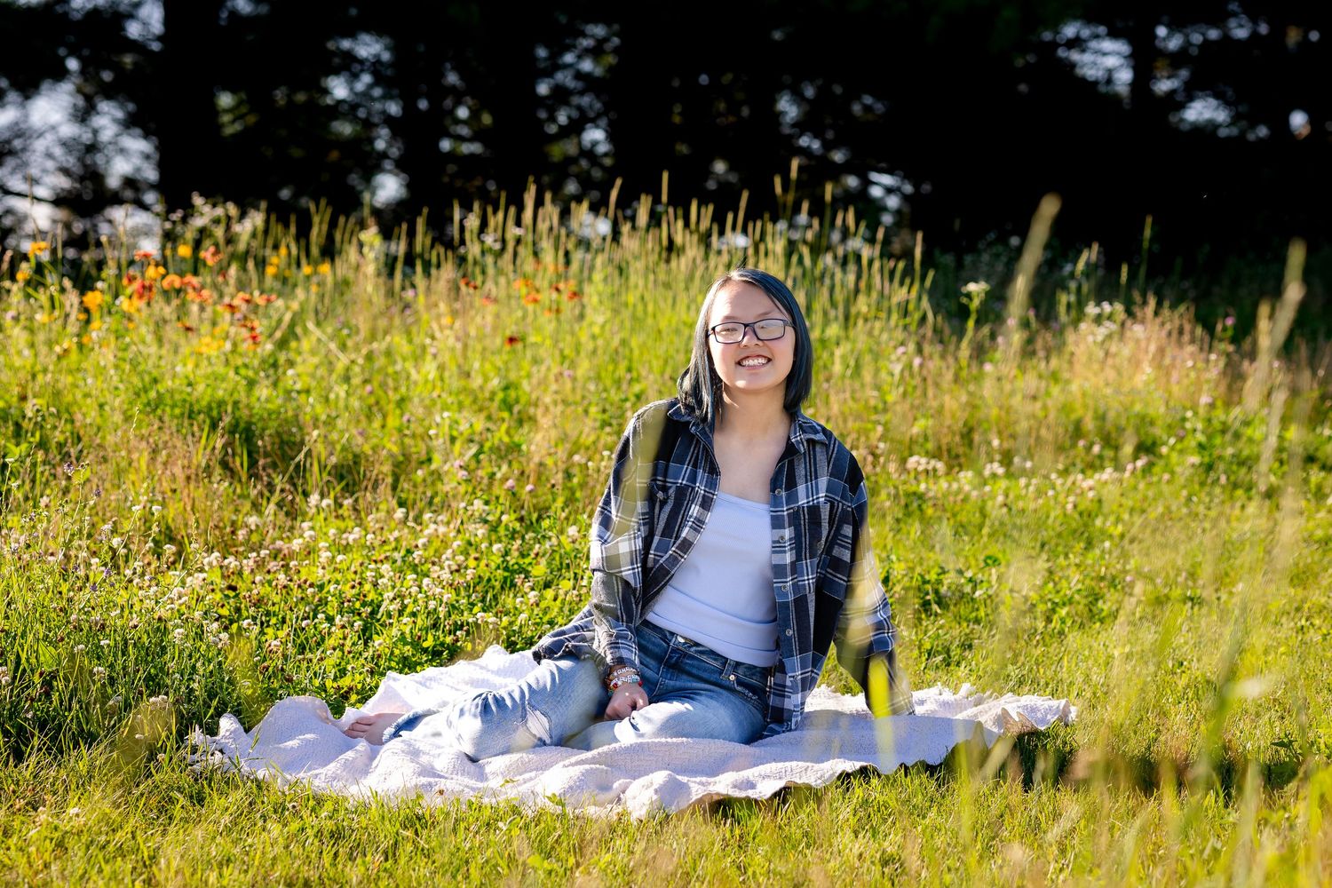 Graduate relaxing on blanket in sunny meadow with wildflowers.