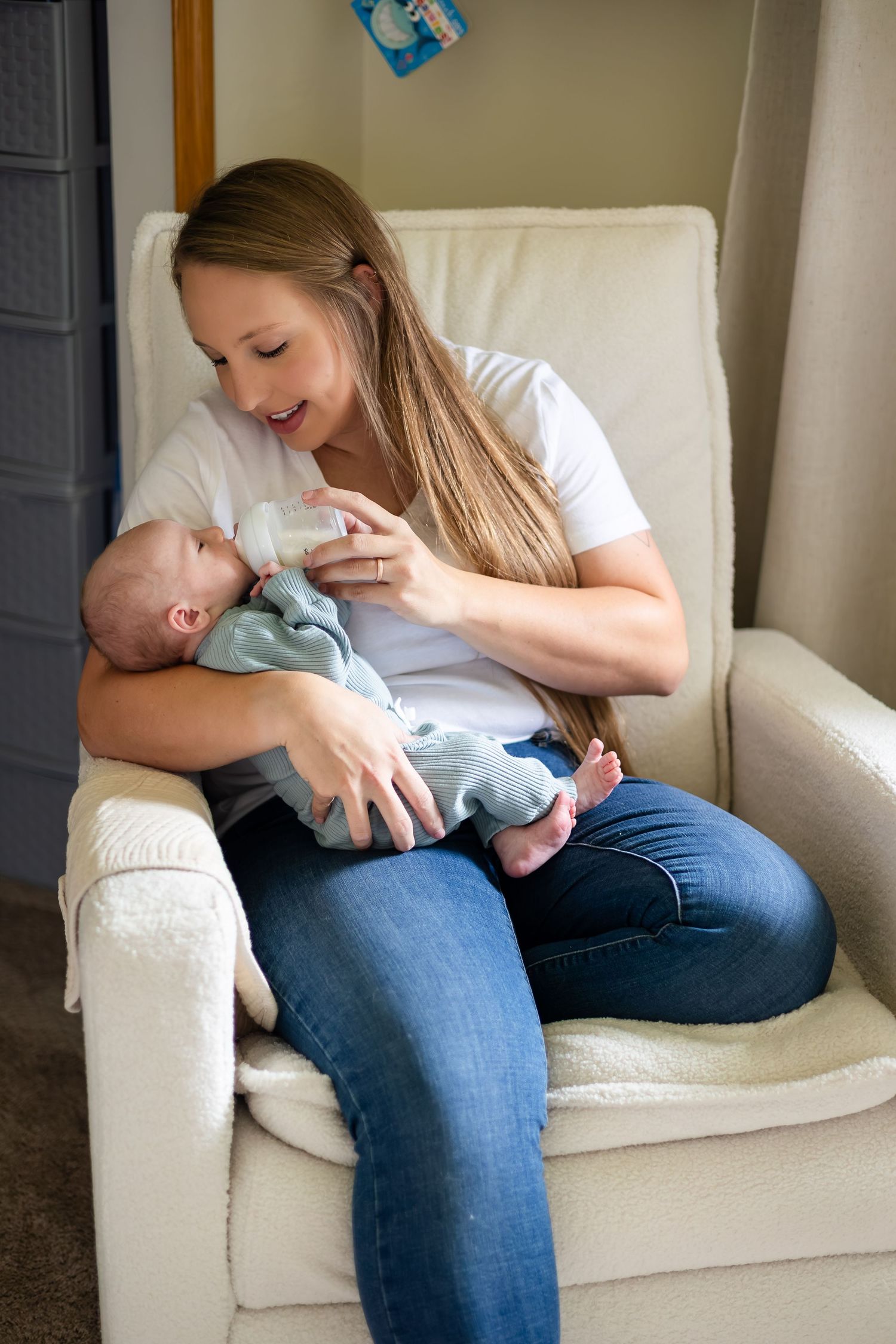 Mother and baby sharing tender moments while sitting in a cozy white armchair.
