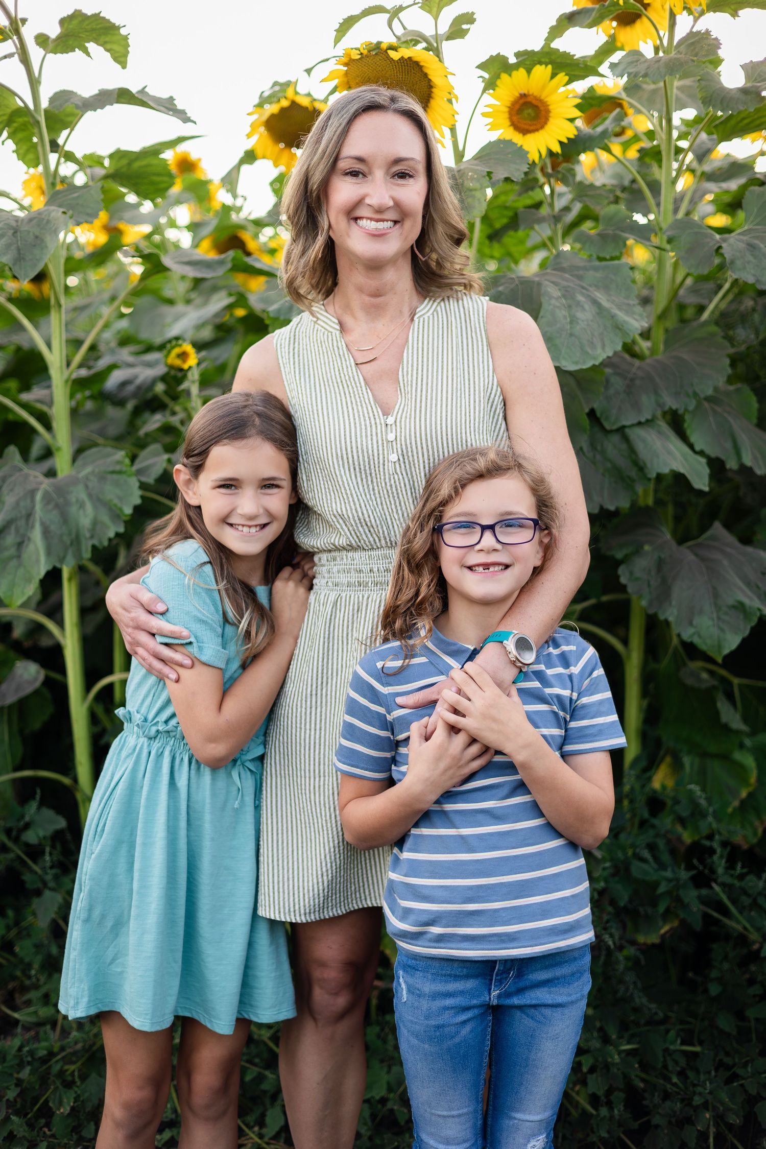 Family group photo with bright sunflowers and natural lighting in summer.