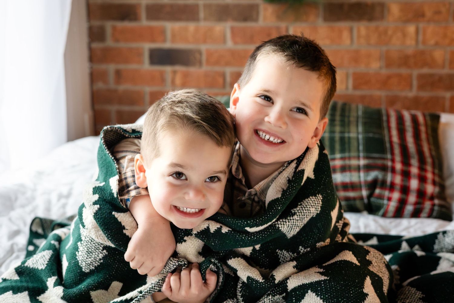 Winter family portrait session with children on a red brick background.