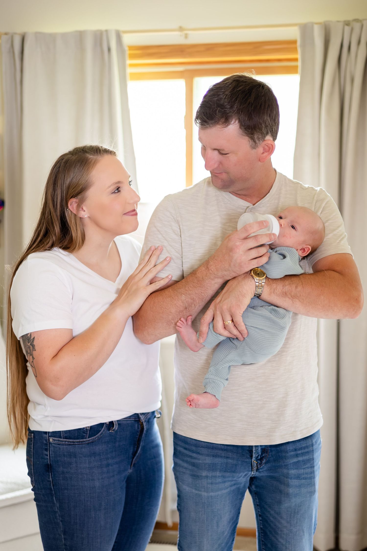 Parents in casual clothing sharing intimate moment with newborn baby.