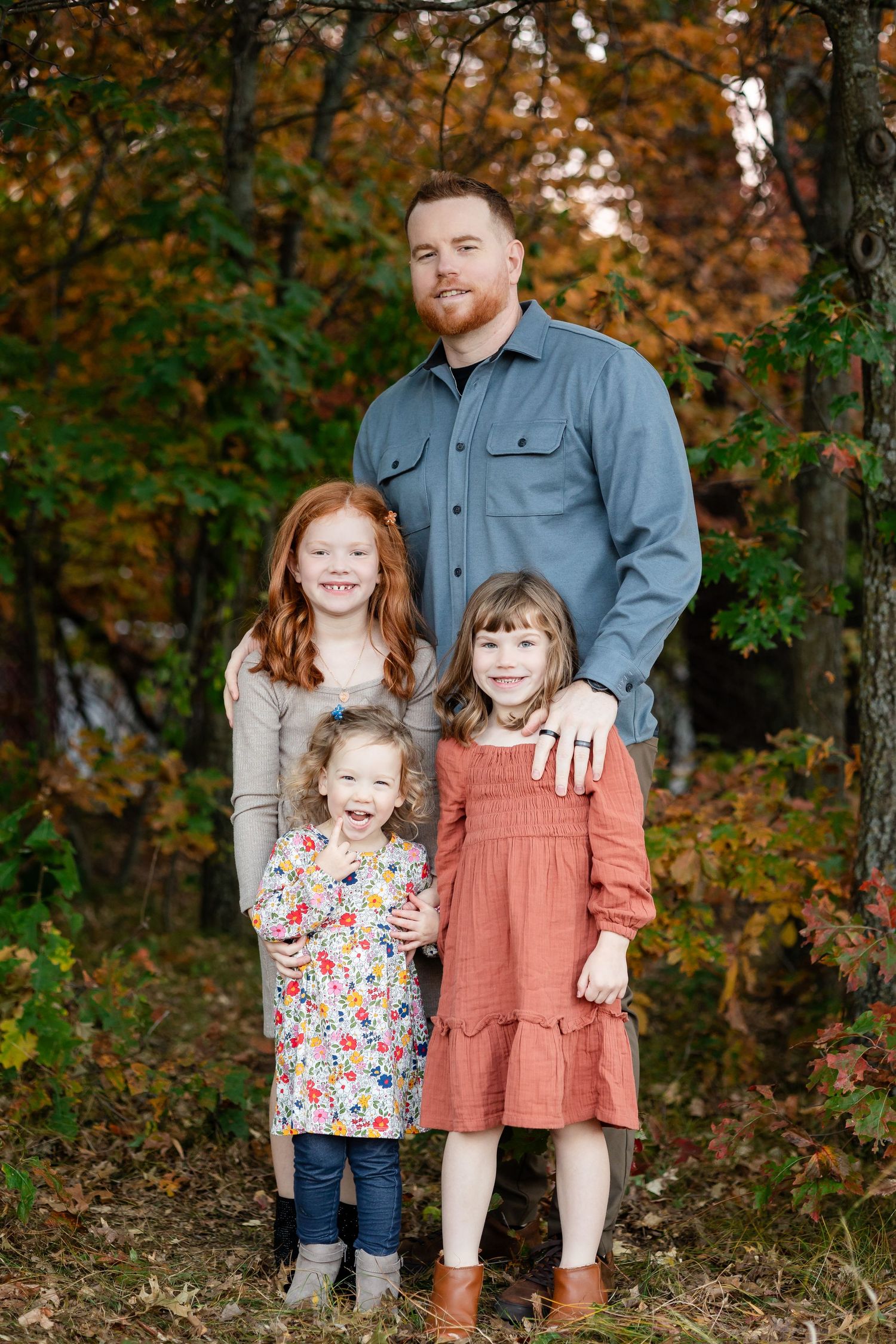 Family group photo in autumn forest with coordinated casual outfits.