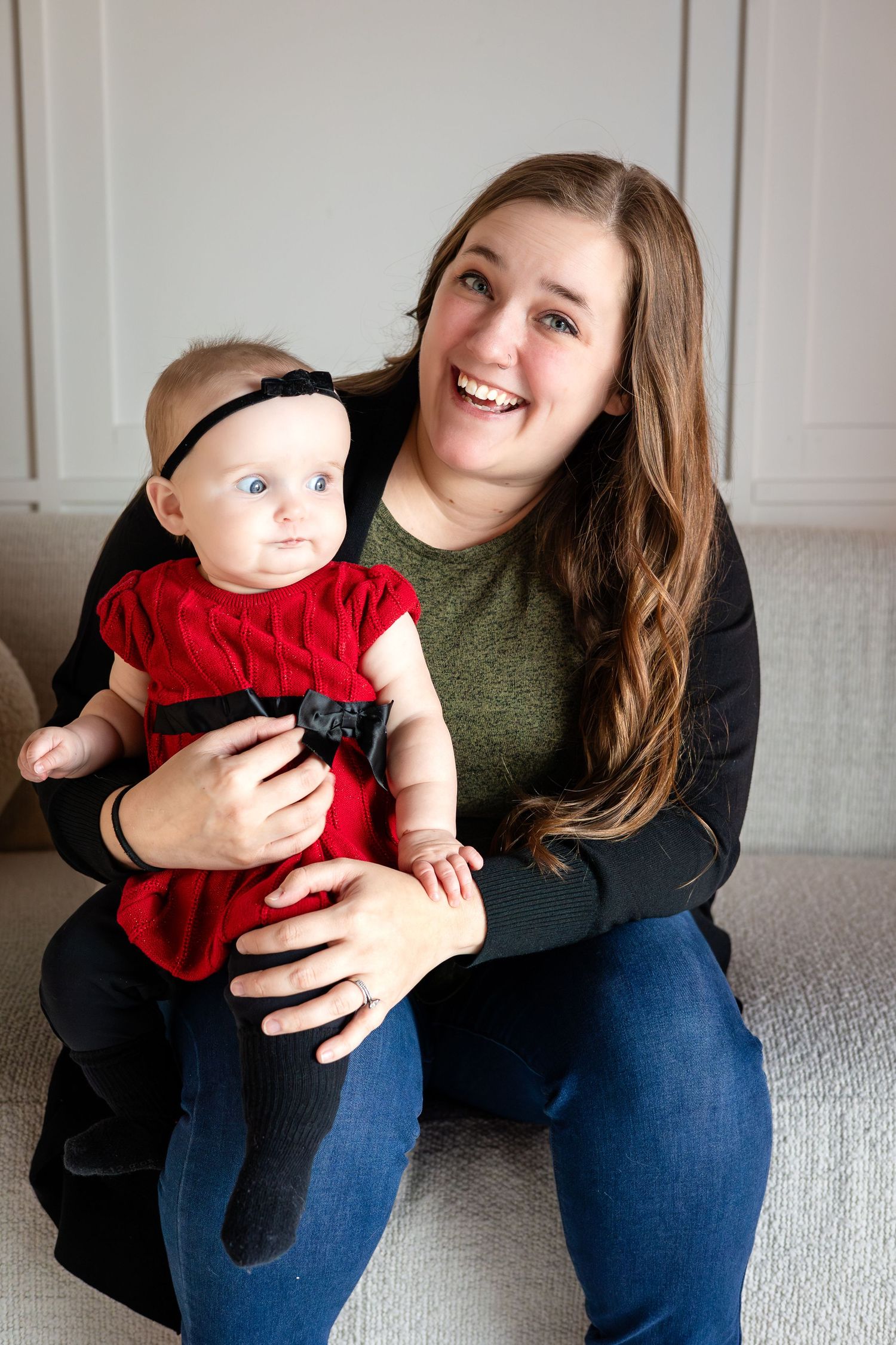 Casual indoor portrait session on a light gray couch wearing winter clothing.