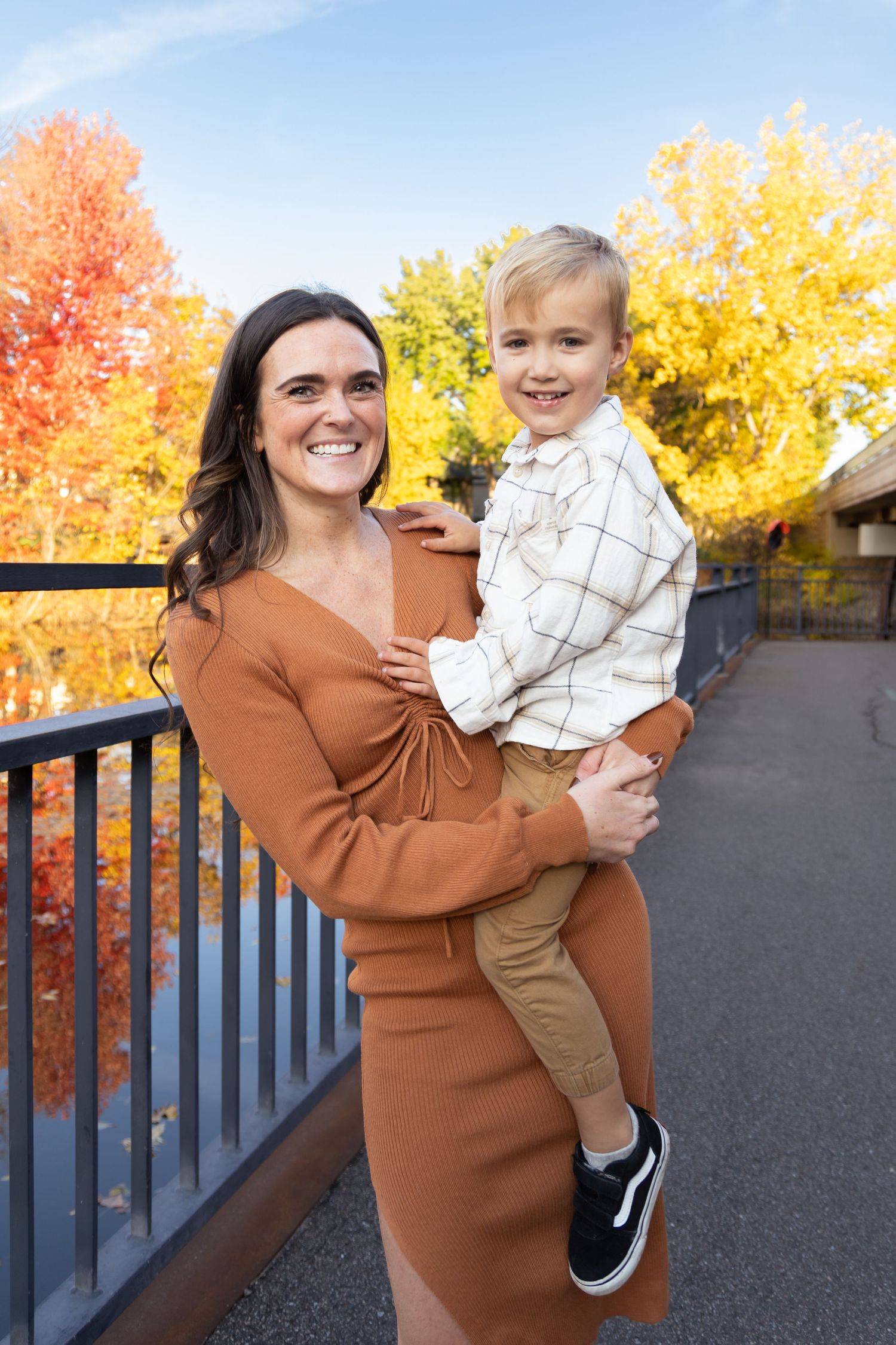 Playful autumn scene with brown sweater and fall foliage in background.