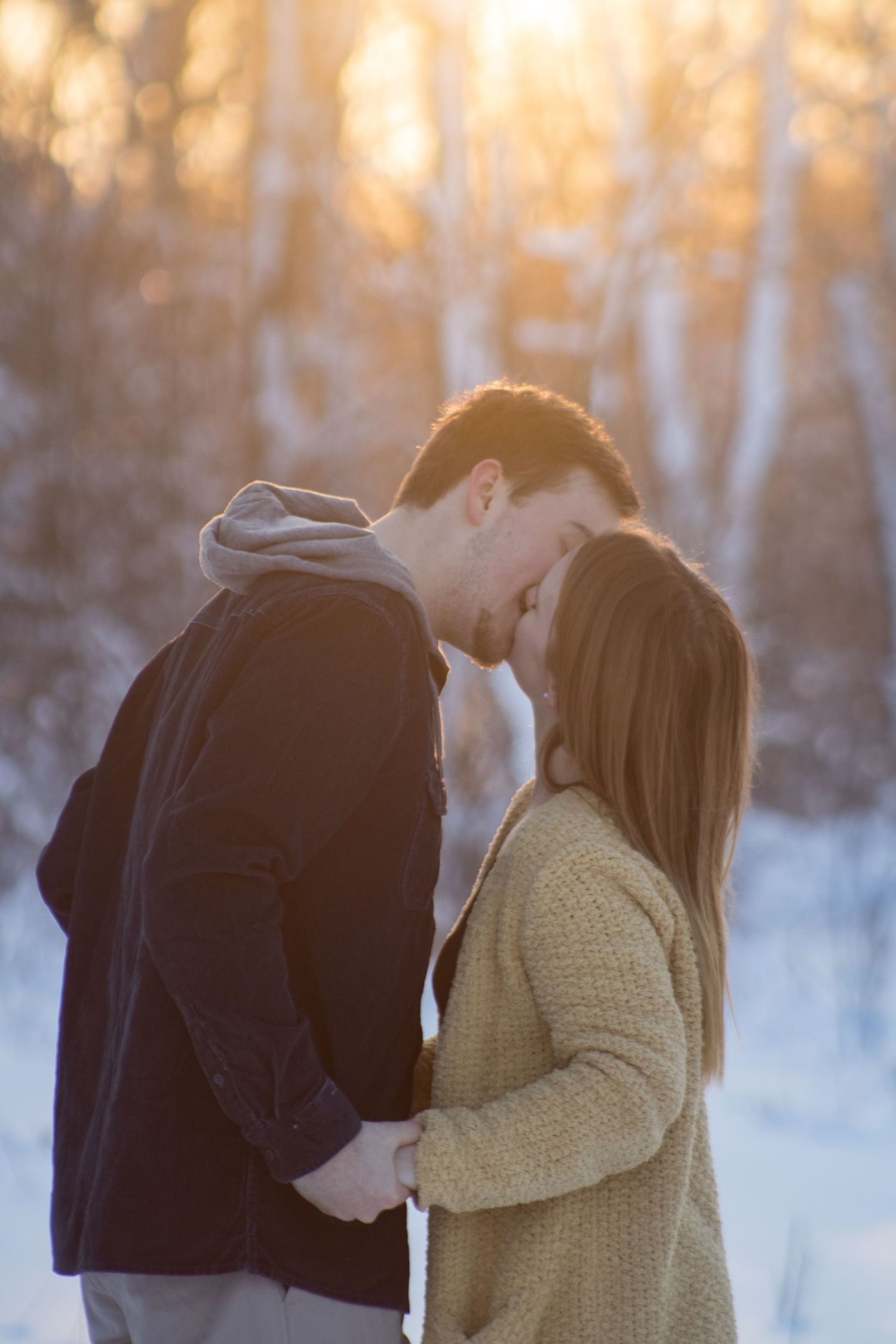 A romantic winter photoshoot sequence with golden sunlight filtering through snow-covered trees.