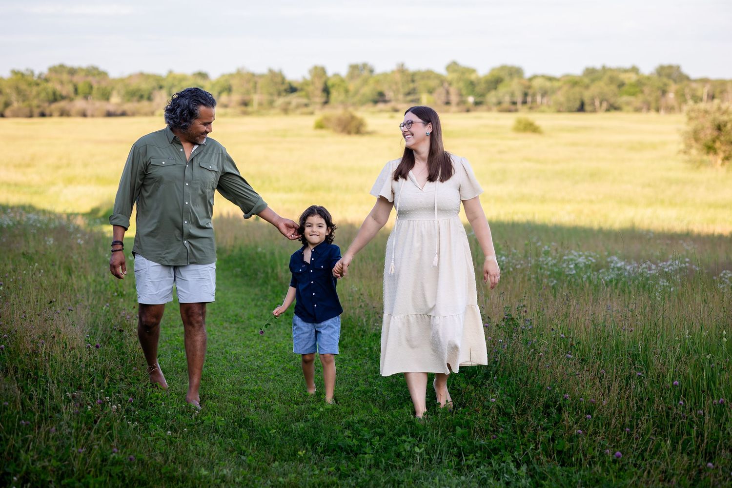 Family walking together through a scenic meadow during golden hour.