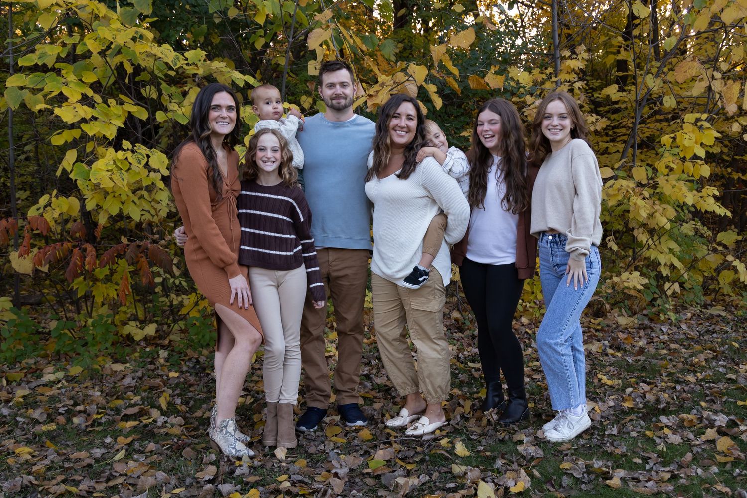 Group portrait in casual attire against colorful autumn trees.
