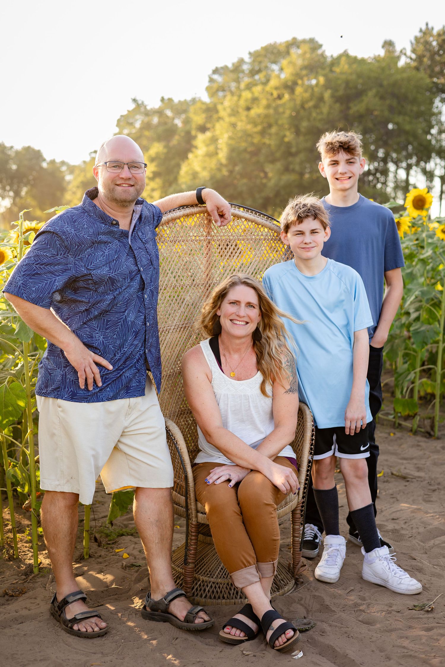 Family poses together in a sunflower field during golden hour with casual summer attire.
