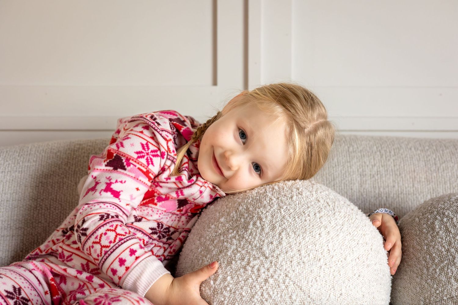 A cozy winter scene with matching pink and white Nordic print pajamas on a gray couch.