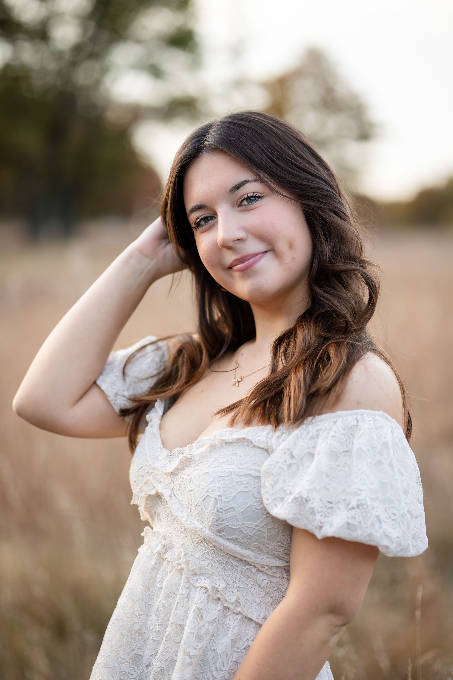 Portrait session on a sunny day wearing a white lace top with flowing hair and natural makeup.