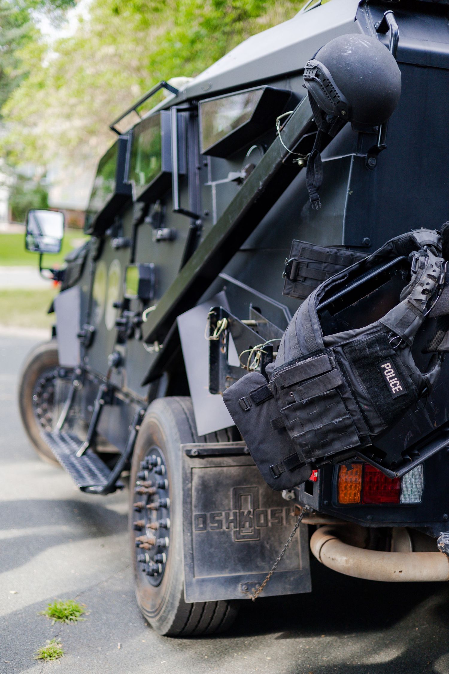 Close-up details of black armored SWAT vehicle equipment and wheels.