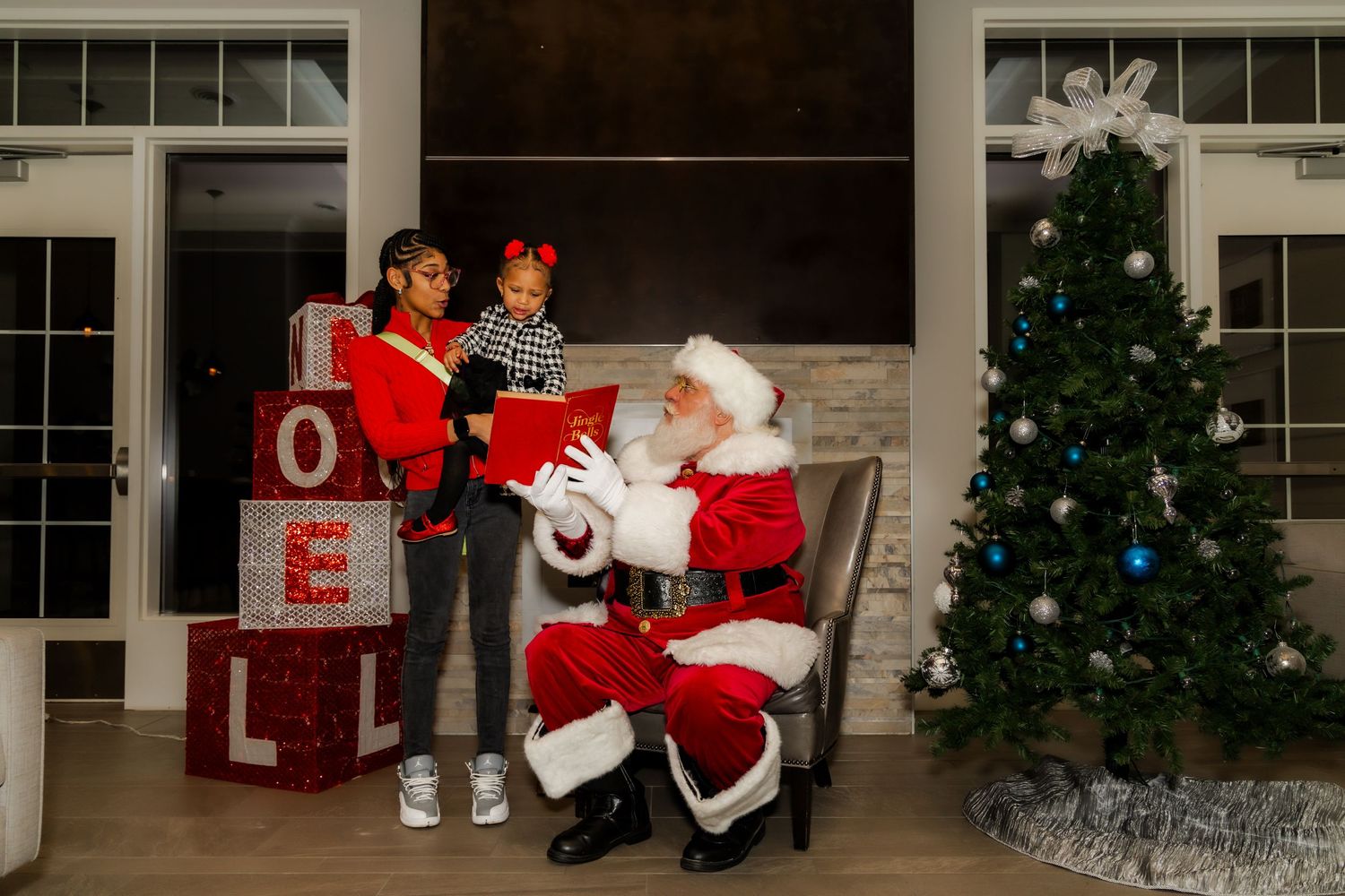 Holiday photo session area with Christmas tree and large NOEL letters on display.