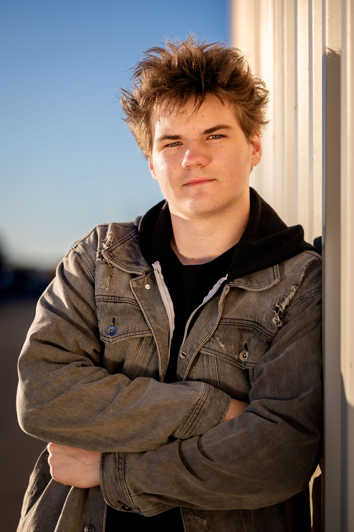 A series of photos showing someone in a brown leather jacket posing against a white pillar outdoors.