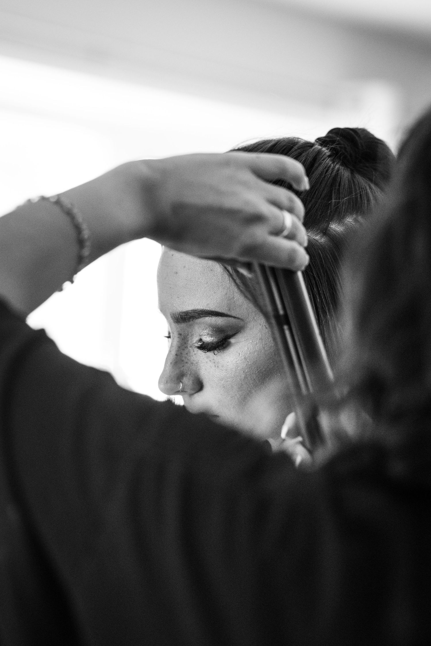Black and white image showing makeup brushes being applied during bridal preparation.