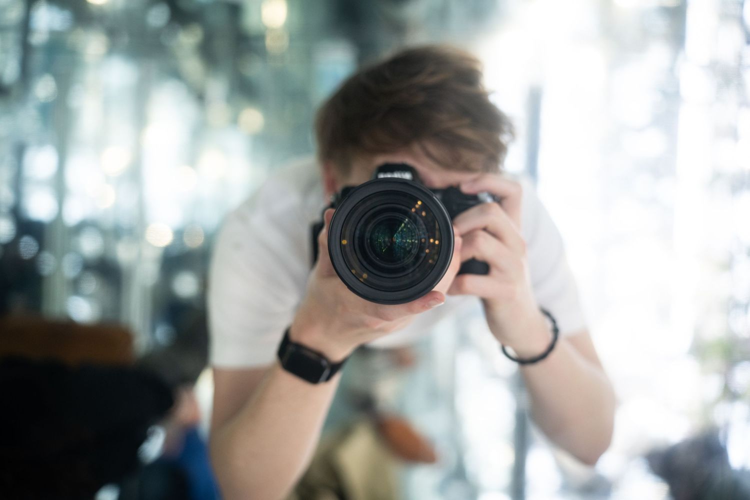 Close-up of photographer taking mirror selfie with professional camera.