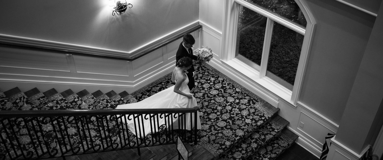 Black and white architectural detail of an elegant ceiling with crown molding and light fixture.