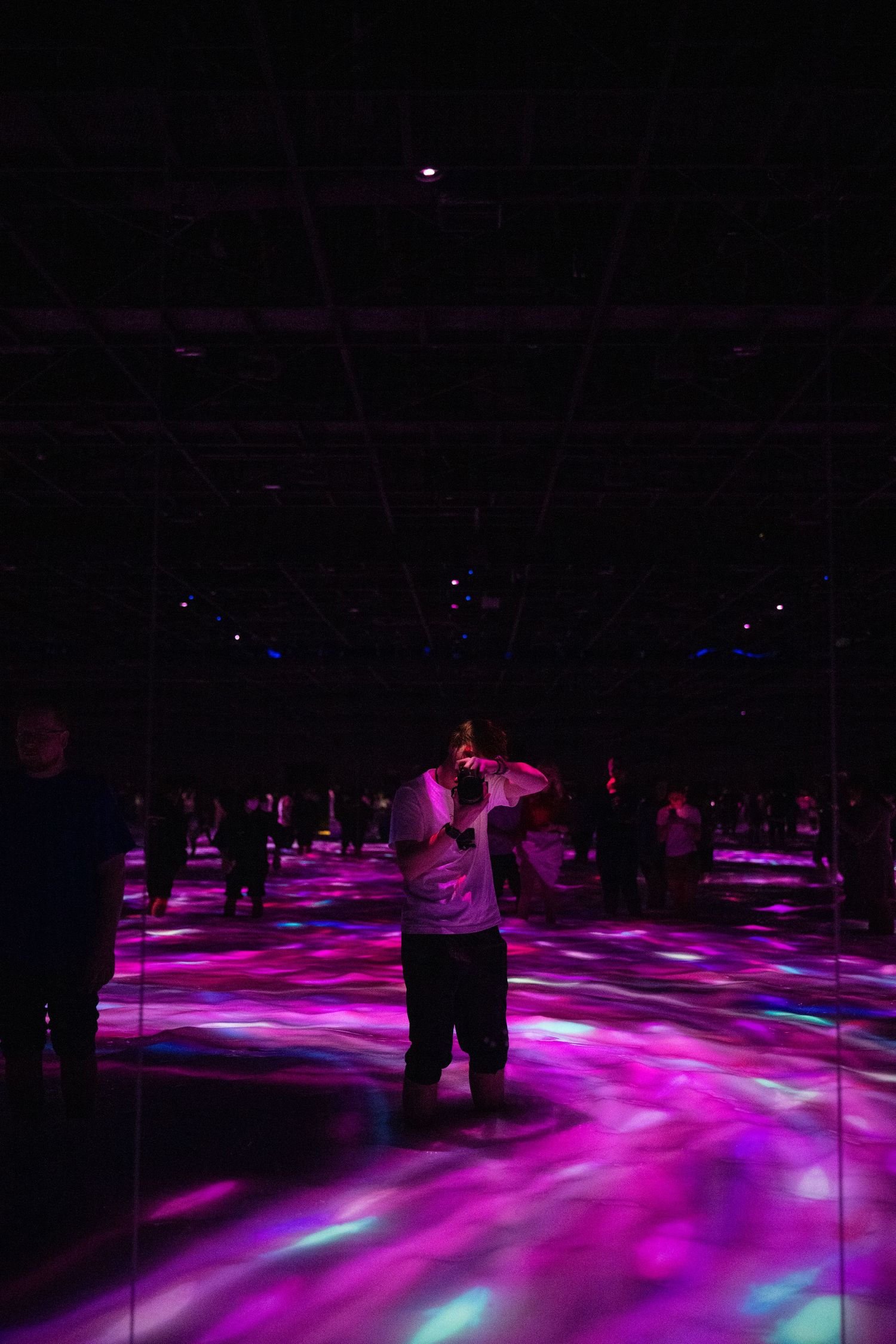 Dancer performing in dark nightclub with purple and pink lighting effects on floor.