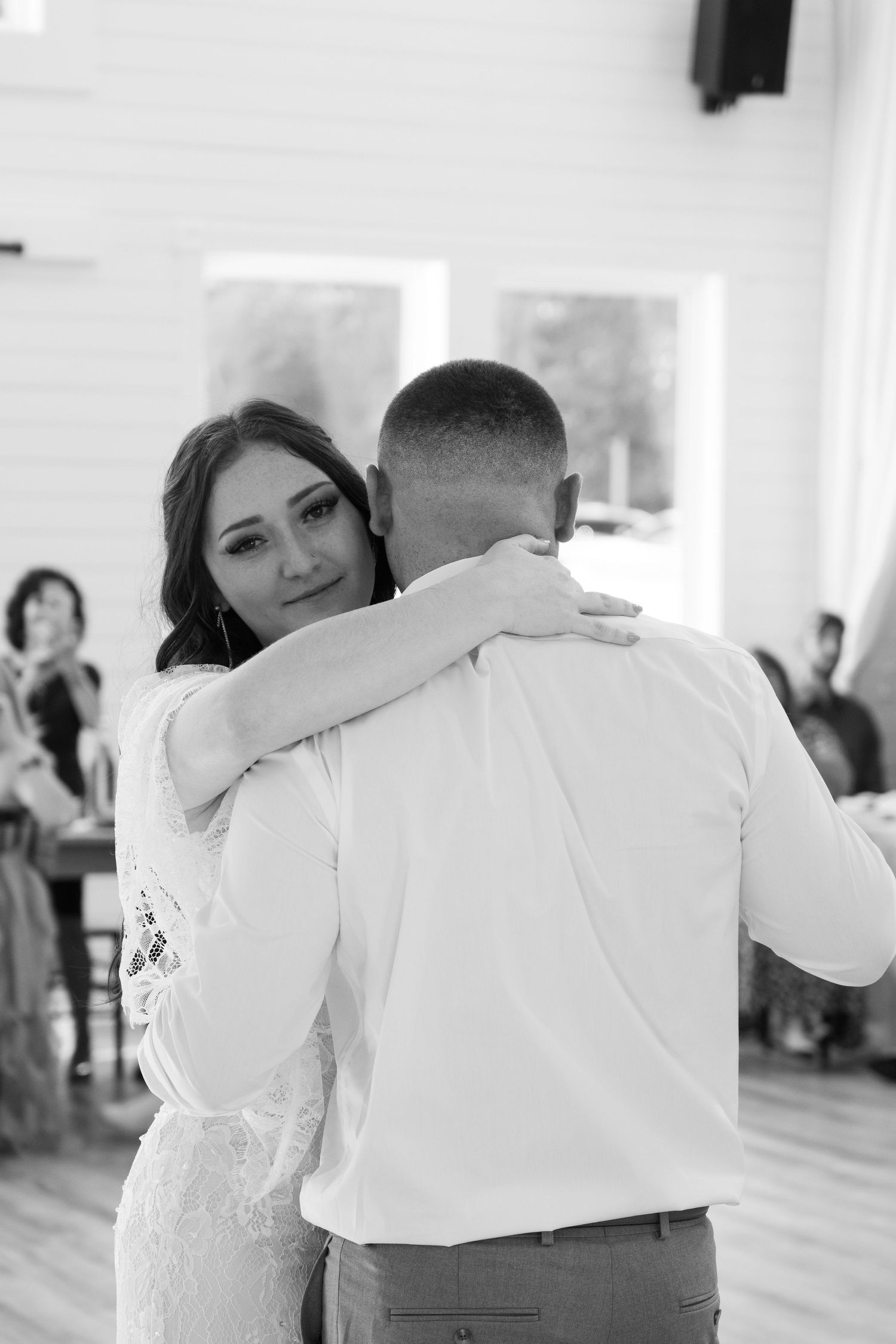 A touching first dance moment captured in black and white at an indoor wedding reception.