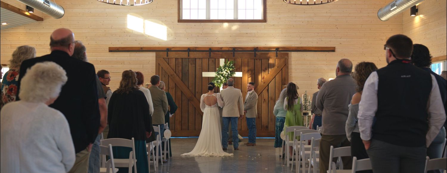 Panoramic view of a wedding ceremony setup in a rustic indoor venue.