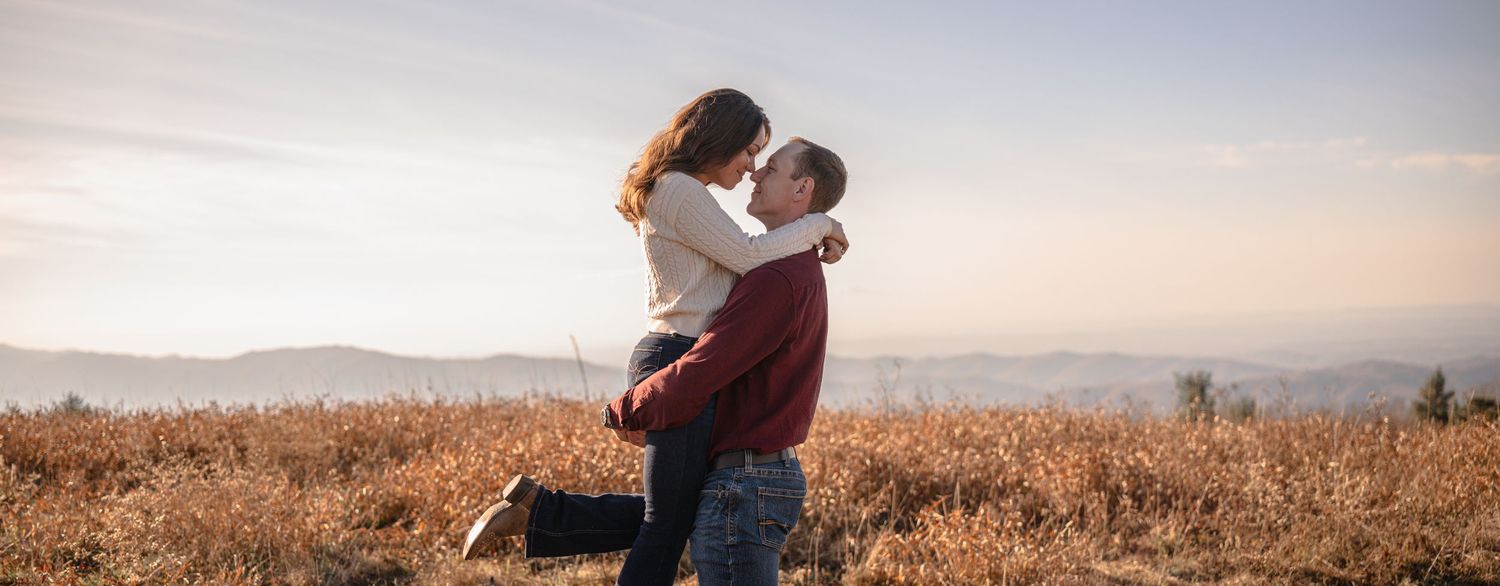 Couple embracing against mountain vista during sunset.