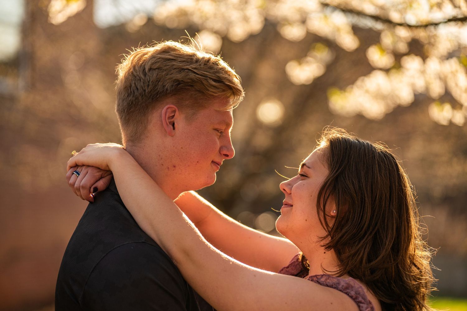 Romantic sunset portrait of couple embracing with golden backlighting.