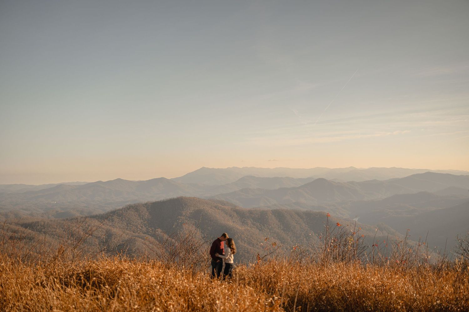 Panoramic view of misty mountain ranges stretching into the distance at sunset.