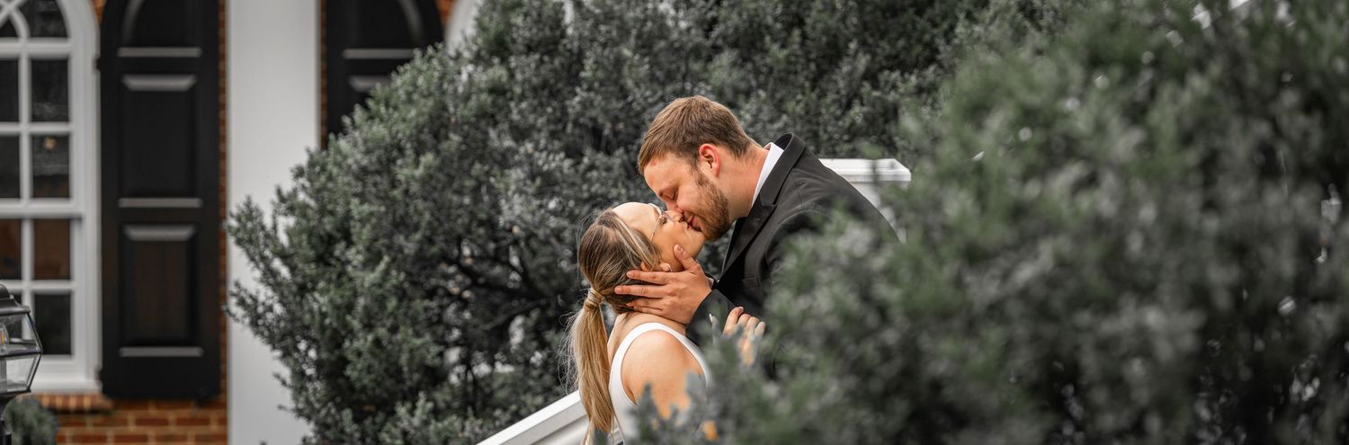 Intimate wedding portrait moment captured against white building exterior.