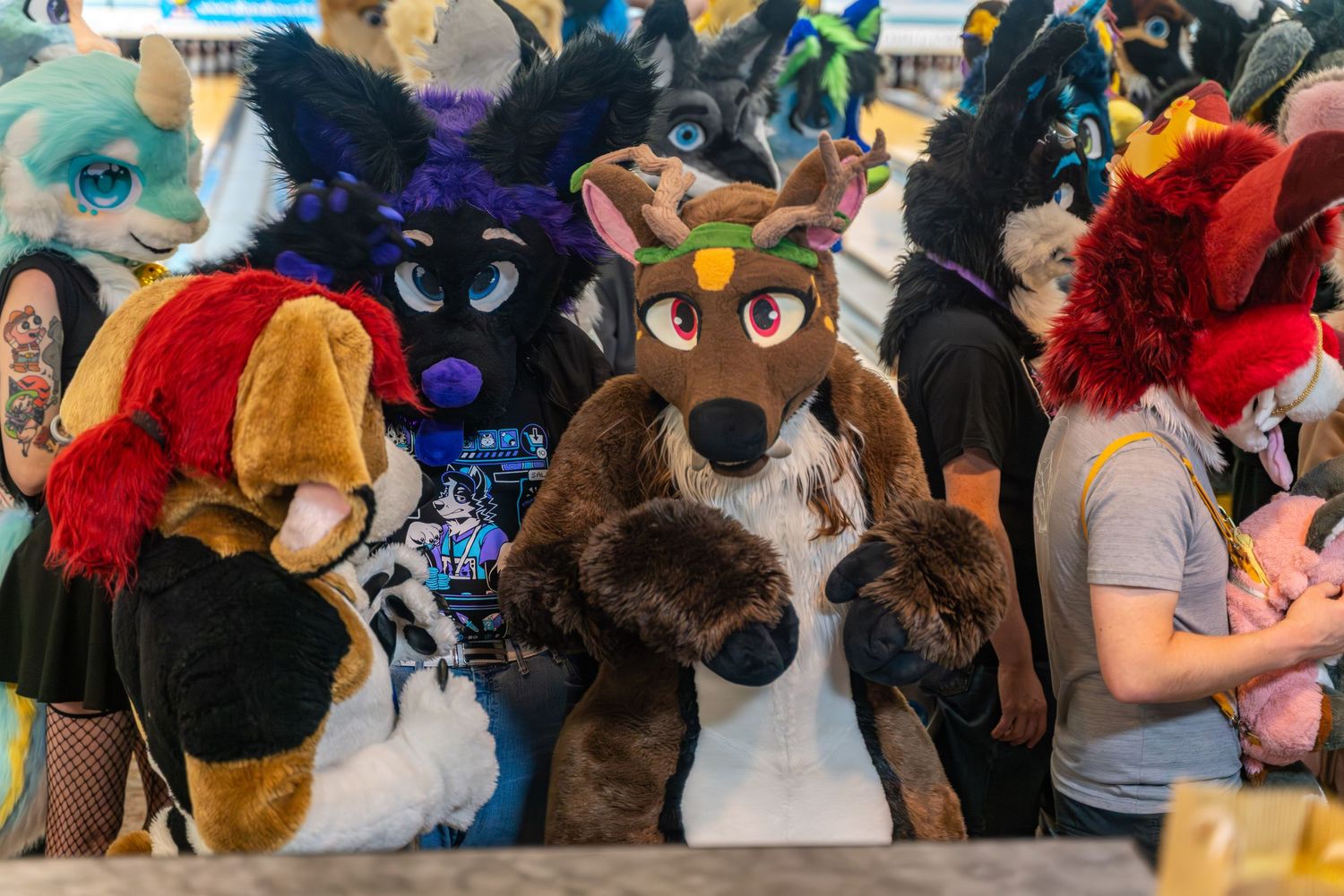 Close-up of fursuit characters with detailed costumes at an indoor gathering.