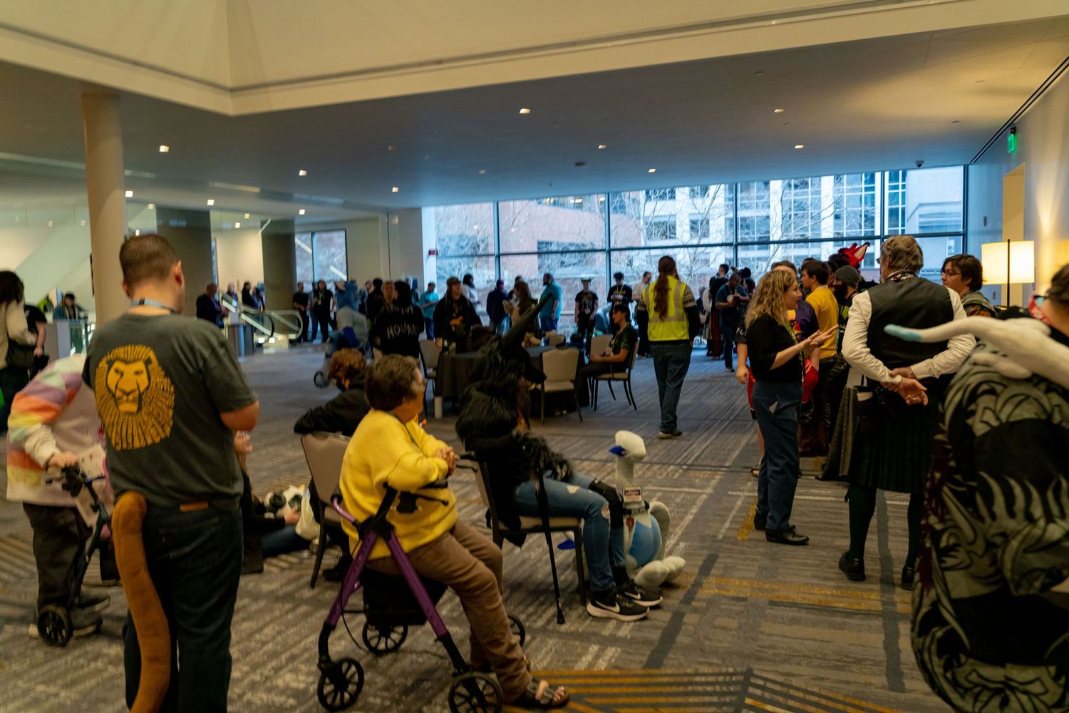 Wide panoramic view of an esports event space with audience members watching competitive gameplay.