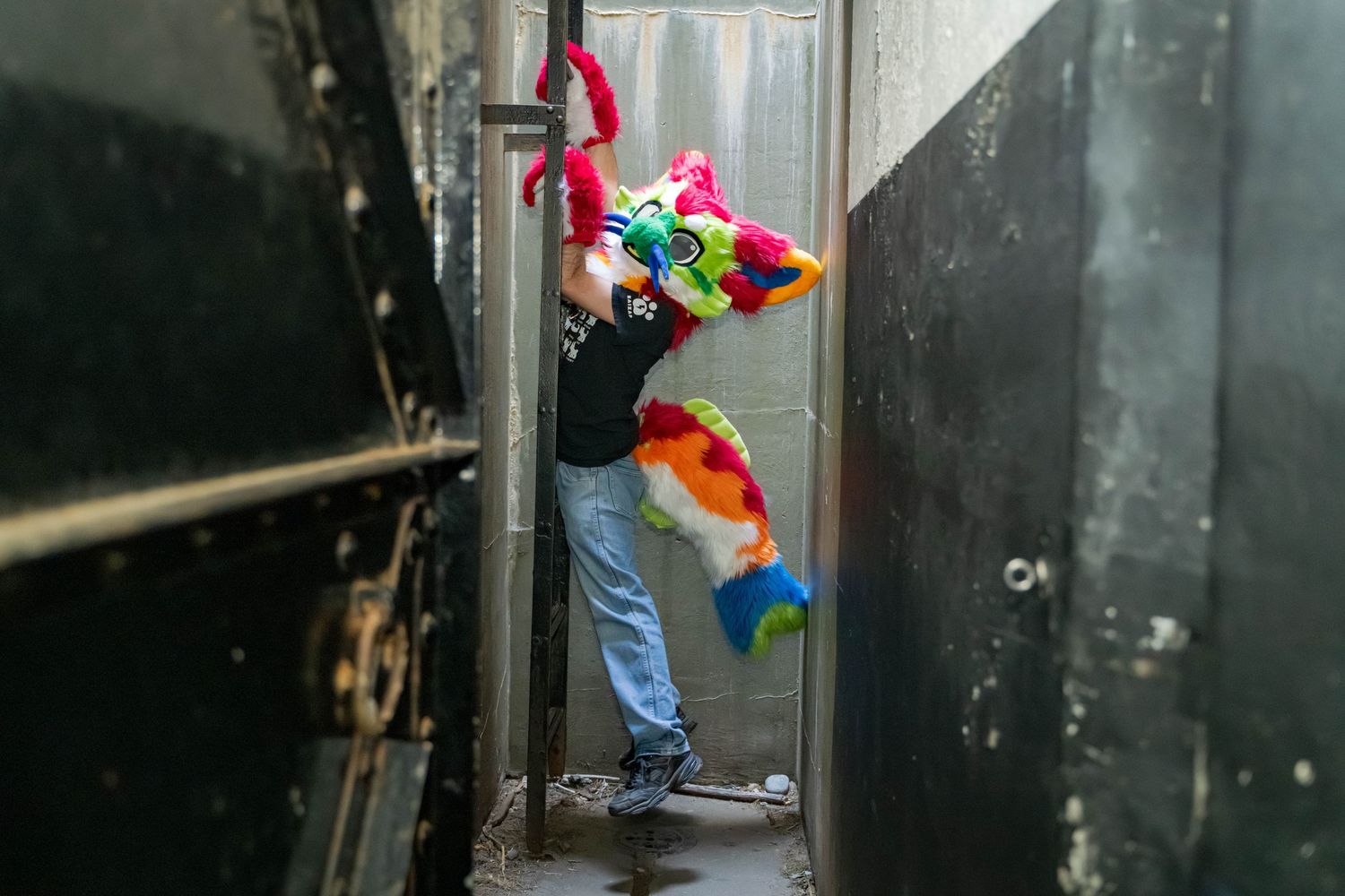 Colorful fursuiters practicing parkour moves inside concrete hallway.