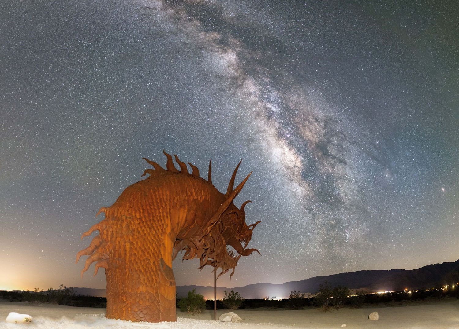 Series of nighttime images showing the Milky Way galaxy arcing over a metal sculpture in a desert landscape.