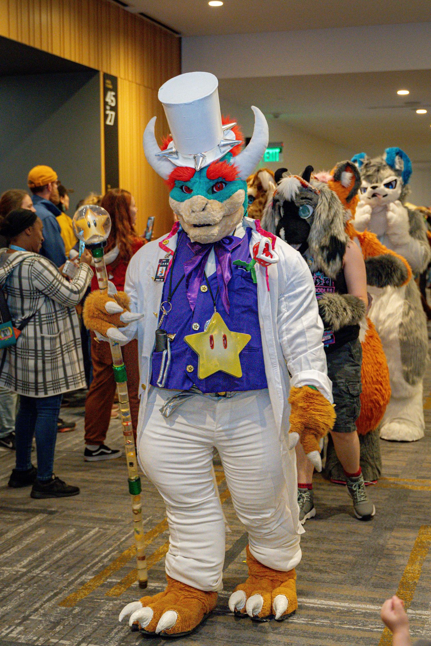 A fursuit character in white overalls and a blue bandana poses at a furry convention.