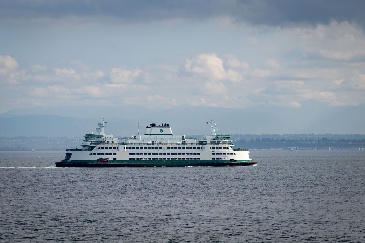 Washington State Ferry crosses Puget Sound waters under partly cloudy skies.