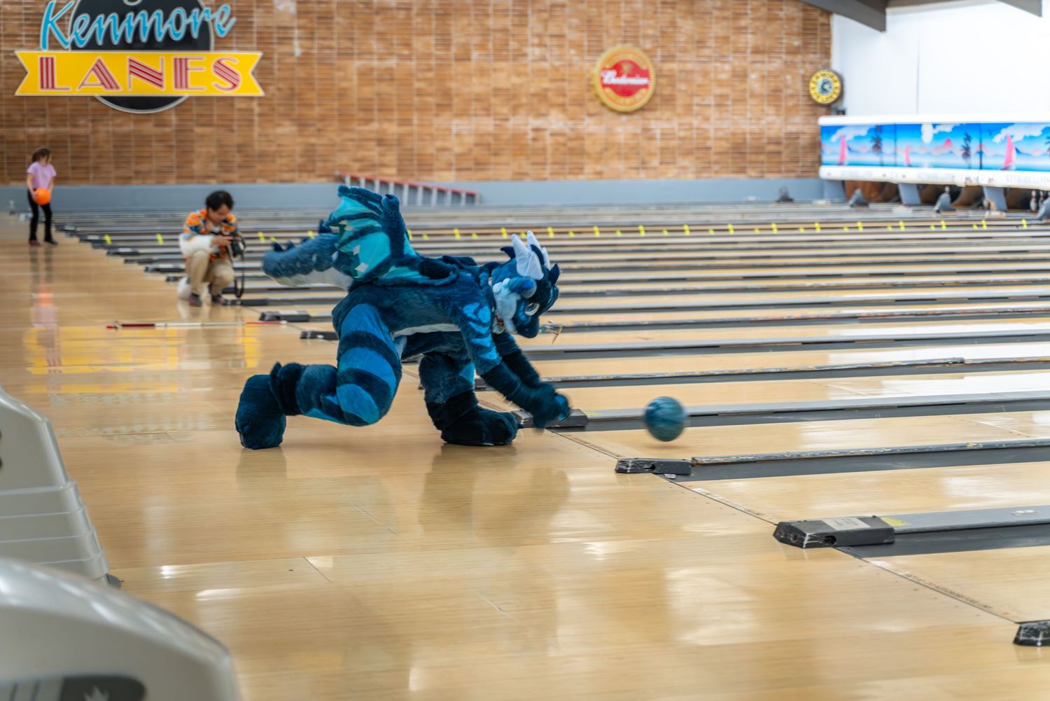 Bowling alley lane with participant in costume releasing a bowling ball.