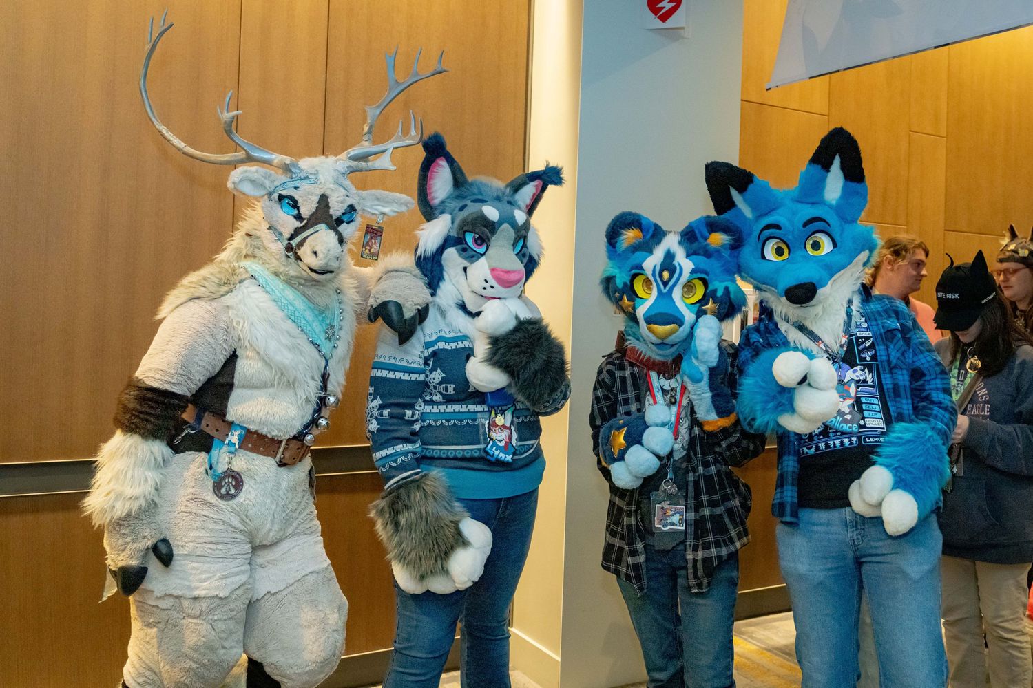 A group of people in blue and white fursuit costumes pose together at a convention or gathering.