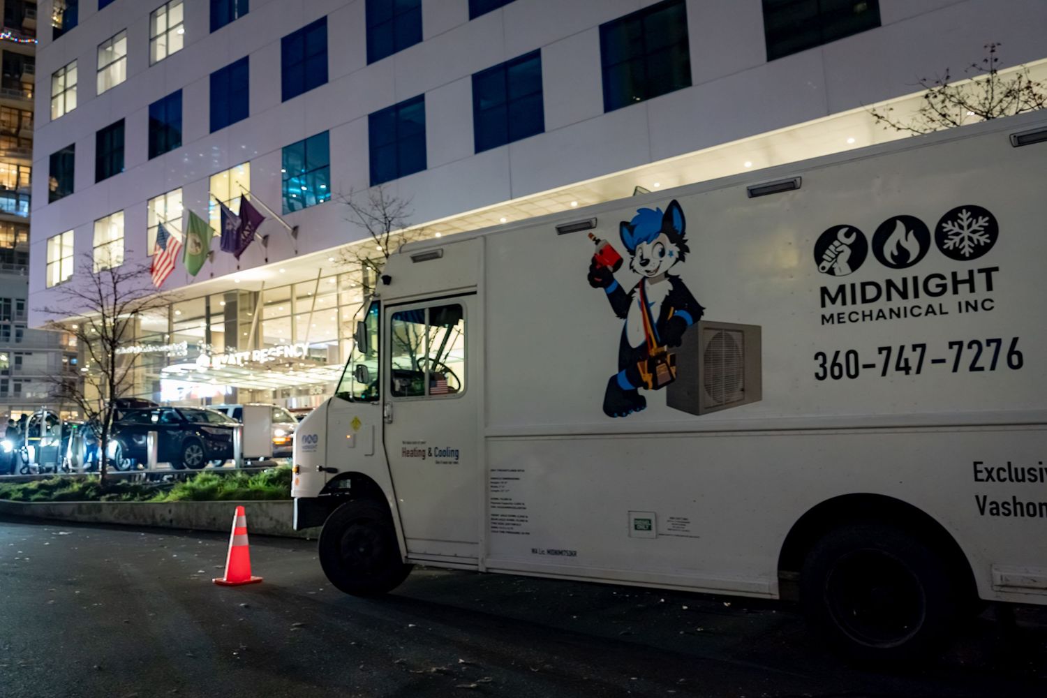 Moving trucks and vehicles parked outside a multi-story apartment building during daytime.