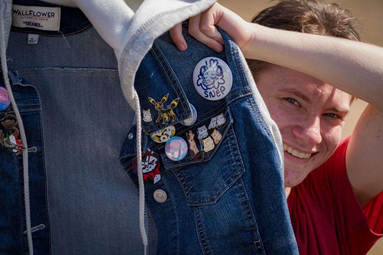 Close-up of a denim jacket displaying various decorative pins and patches.