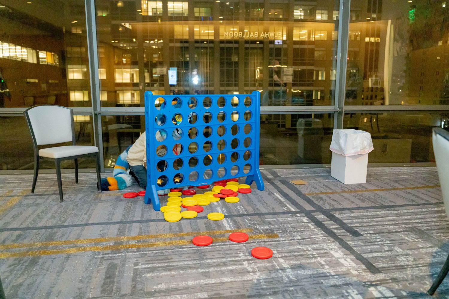 A row of Connect Four games set up on an outdoor patio deck with buildings visible in the background.