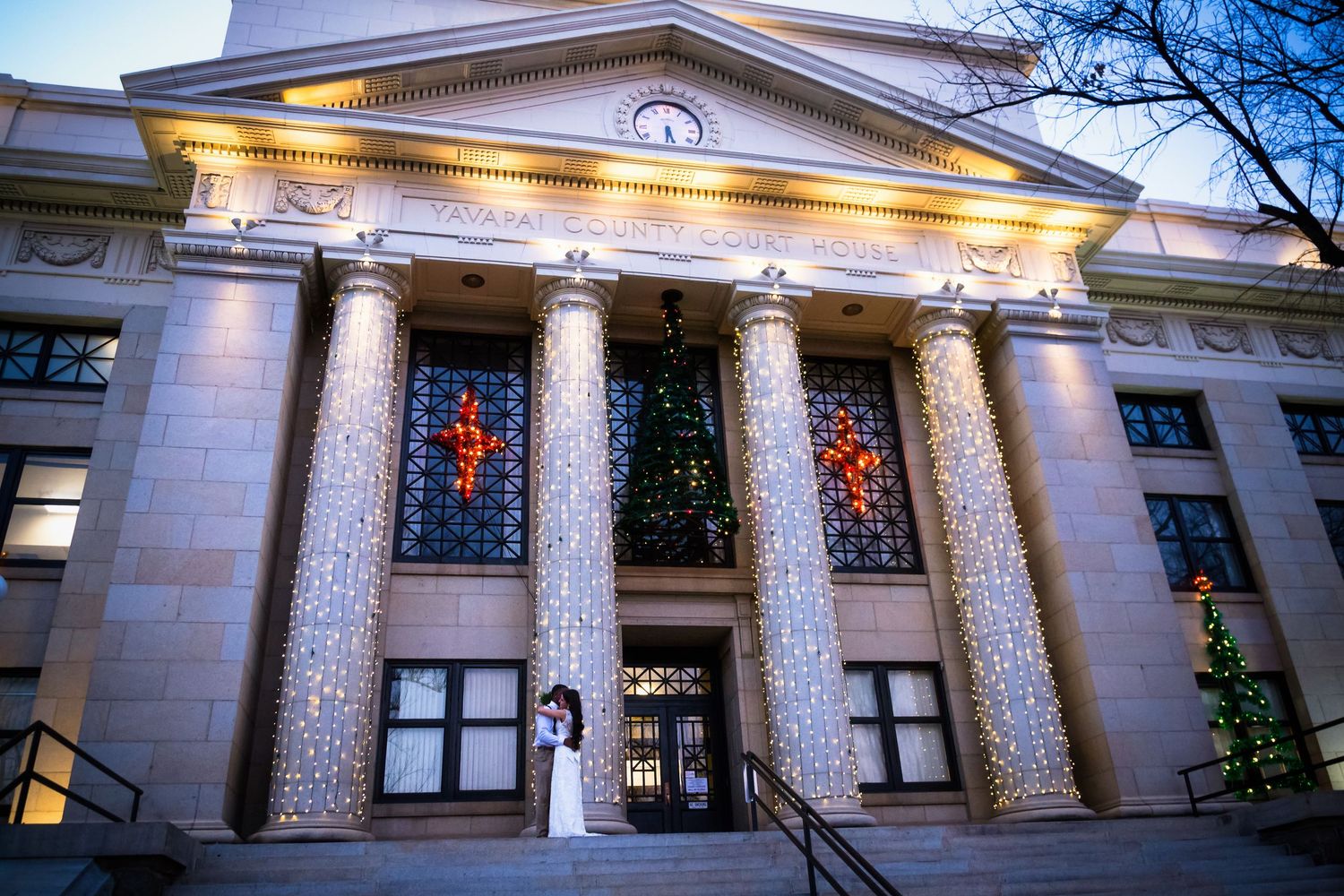 Illuminated neoclassical building facade with columns and Christmas decorations at night.