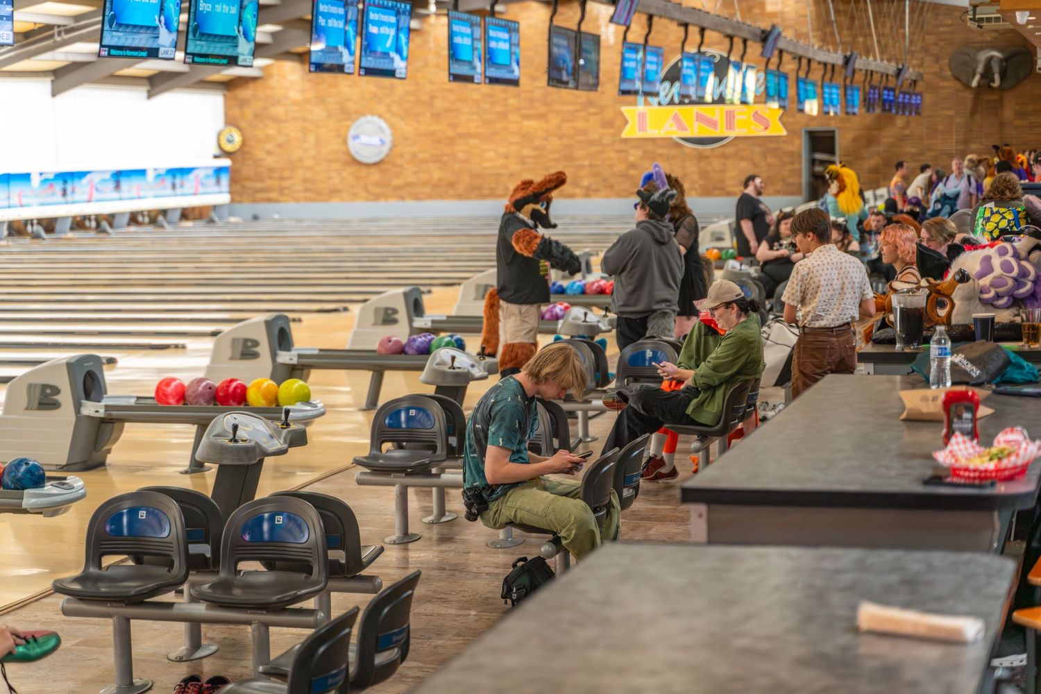 Wide view of bowling alley showing seating area and scoring monitors mounted above lanes.