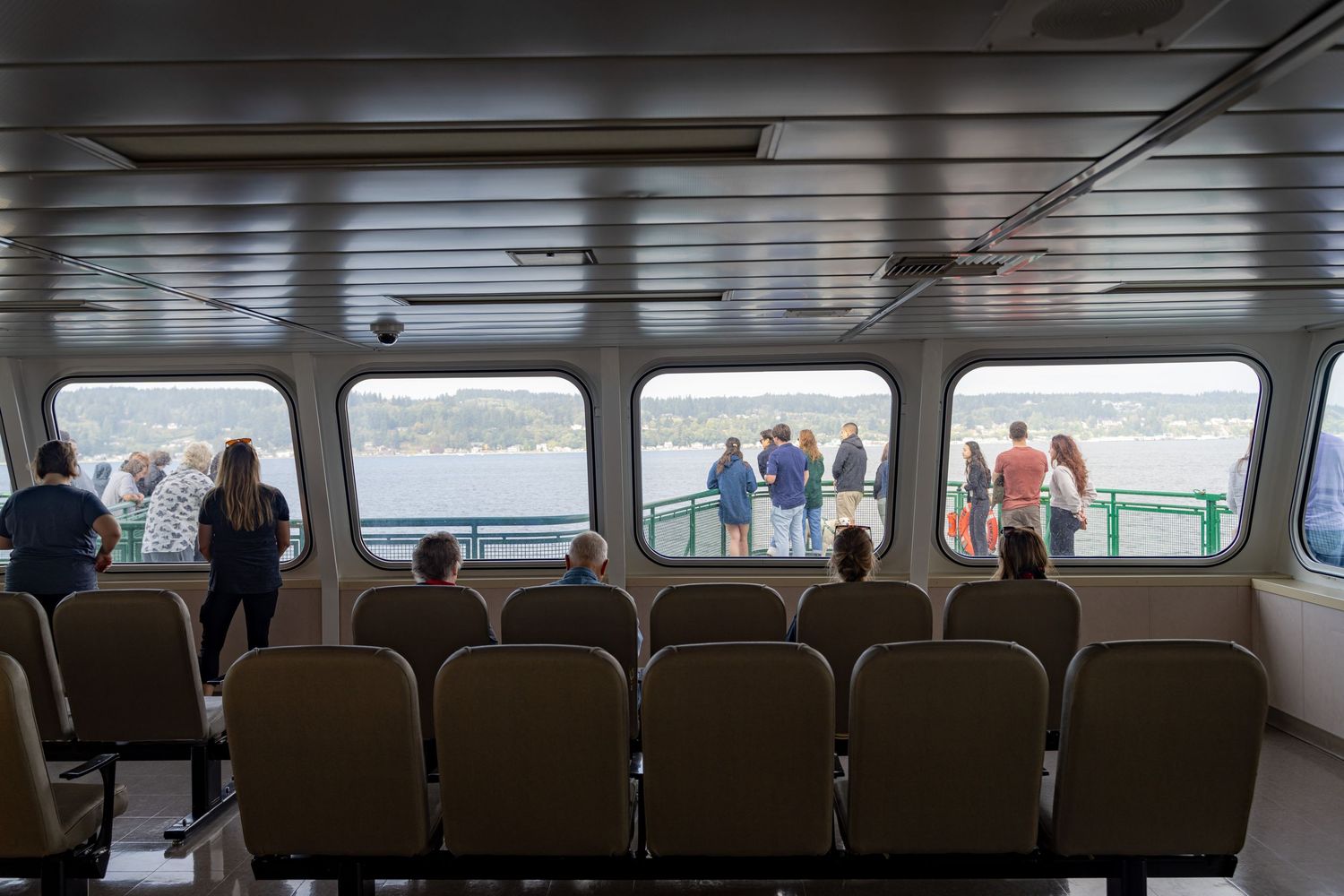Interior passenger seating area on ferry with rows of seats and window views.