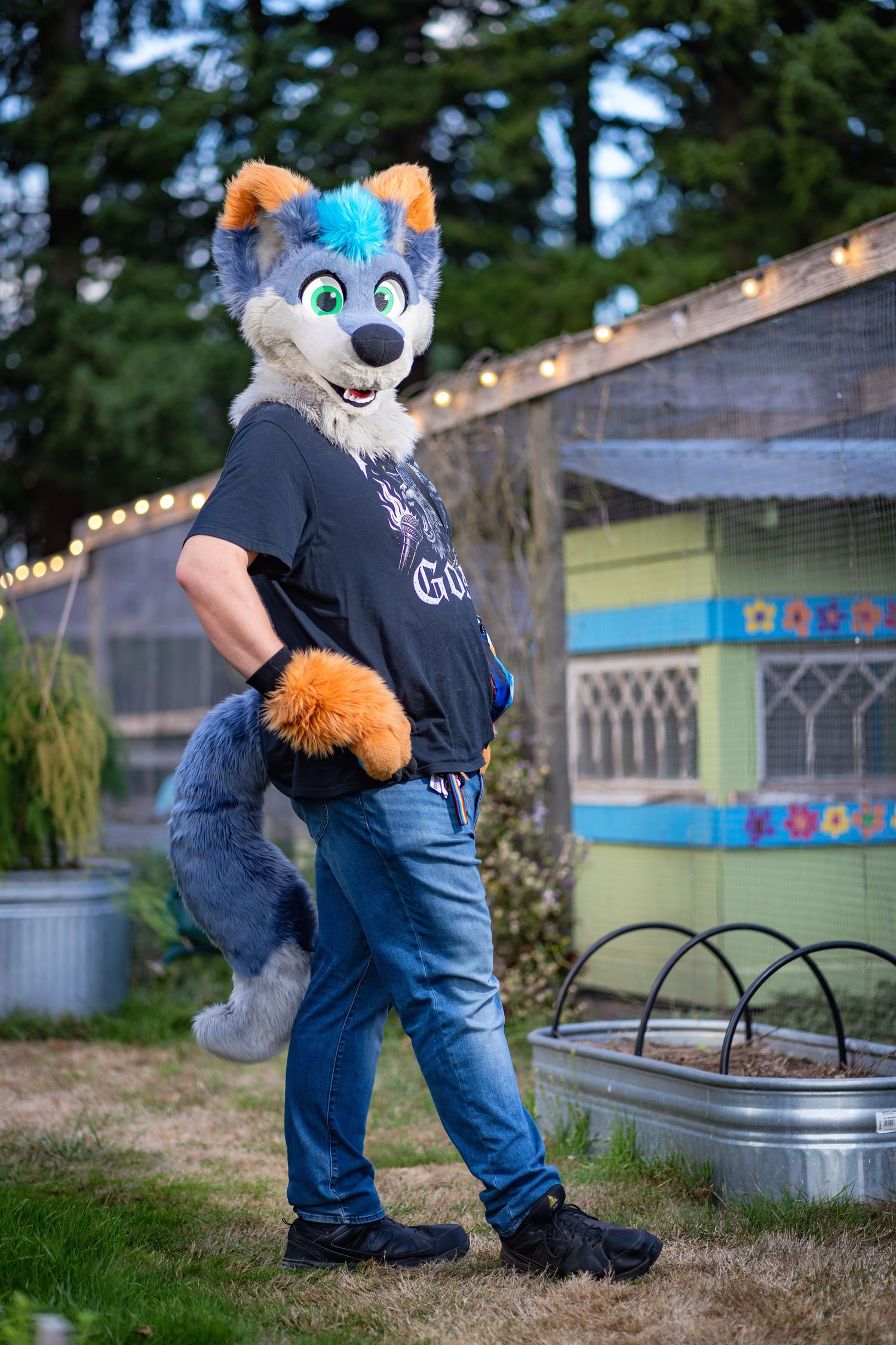 Animal fursuit characters in blue jeans and black shirts stand near decorative lighting outdoors.
