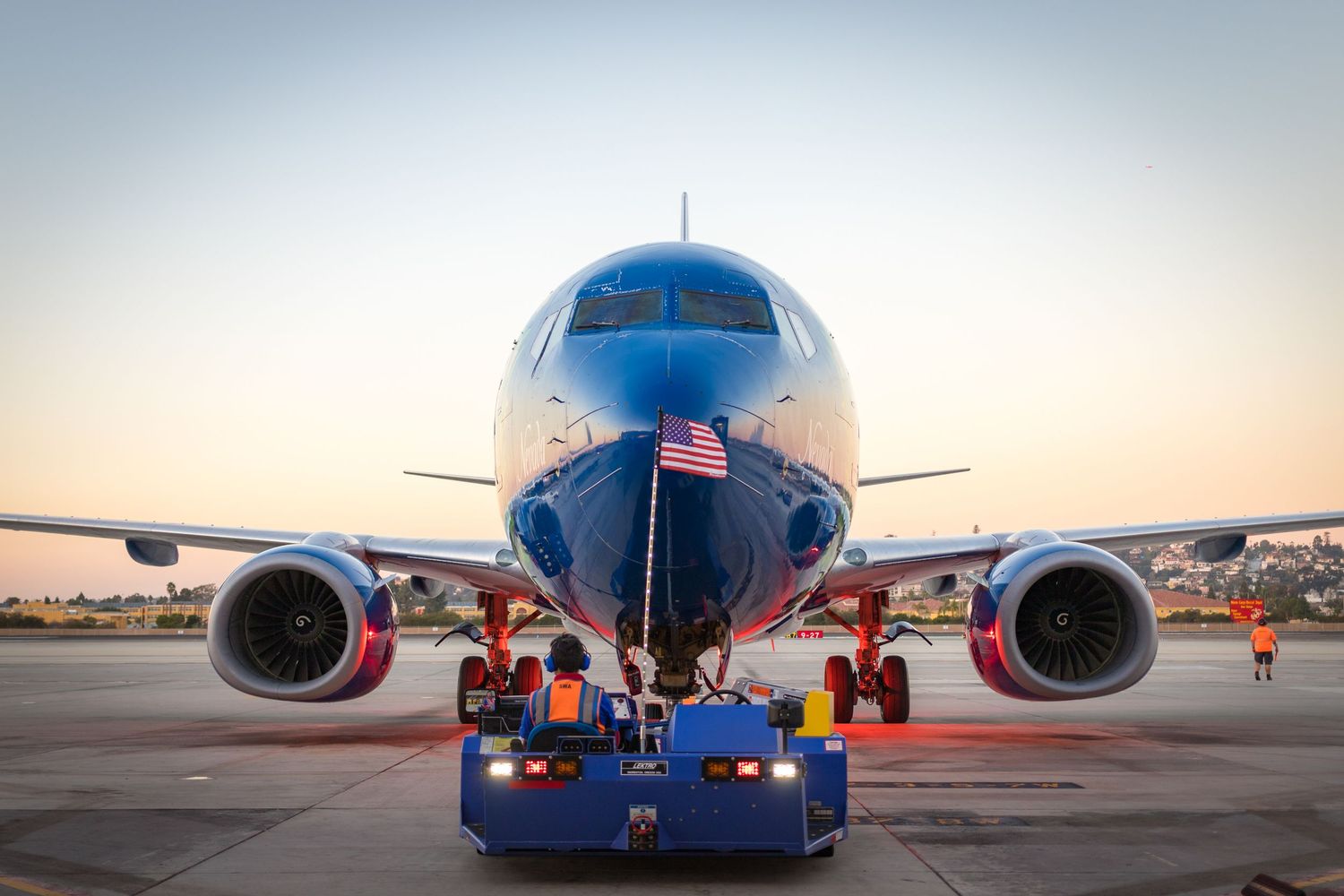 Commercial aircraft on tarmac during sunset with ground equipment visible.