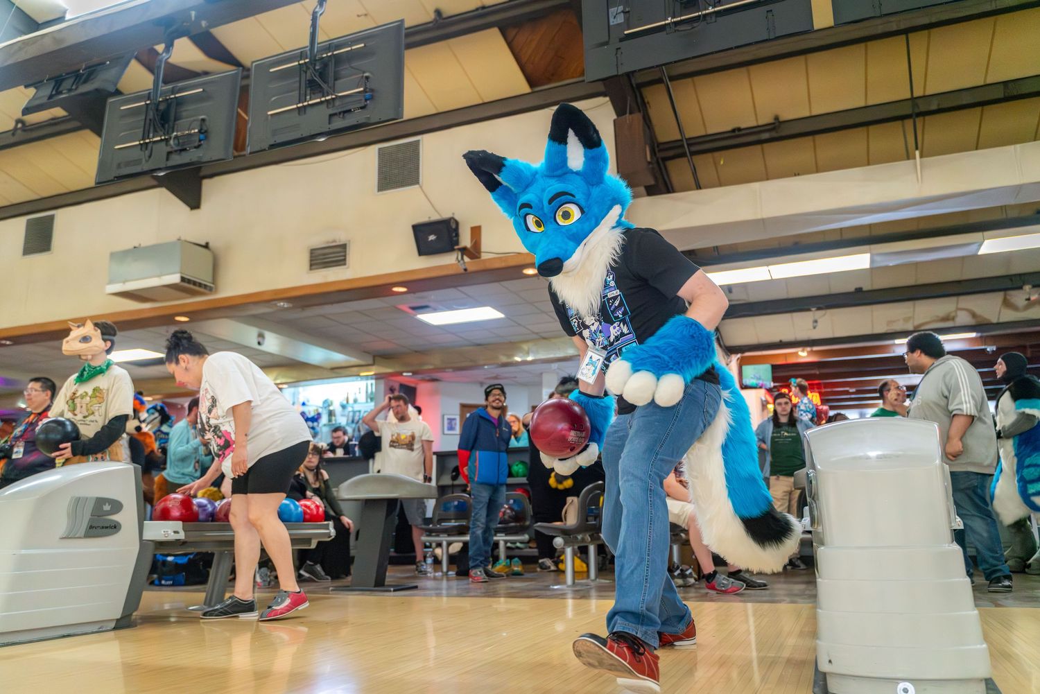 Row of blue mascot characters posed in a bowling alley setting.