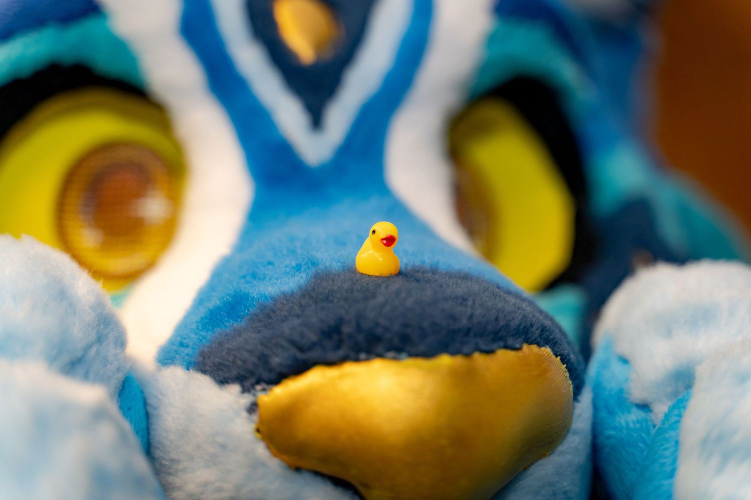 Yellow rubber duck sits atop blue and white swirled bath foam creating a playful bathtub scene.