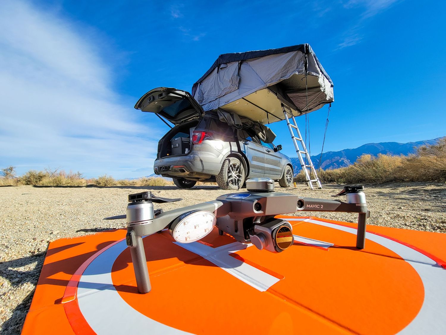 Close up view of an orange adventure motorcycle against bright blue sky in desert terrain.