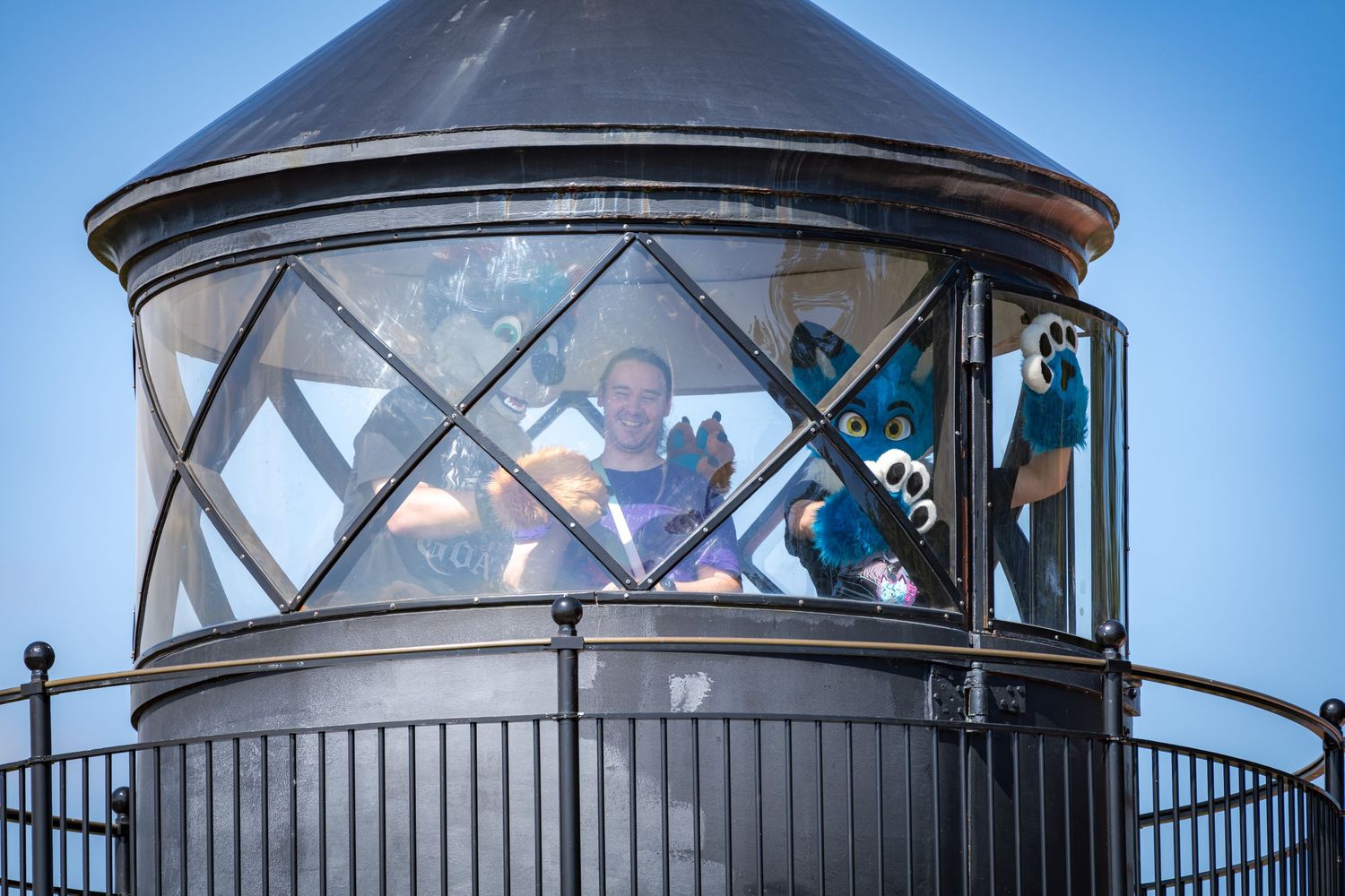 Close-up view of lighthouse lantern room with diagonal glass panes and metal framework.