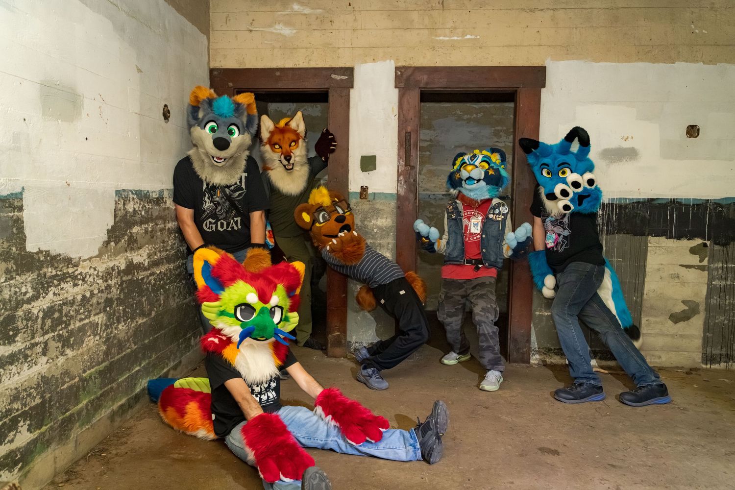 Colorful fursuit characters pose inside a concrete bunker structure.